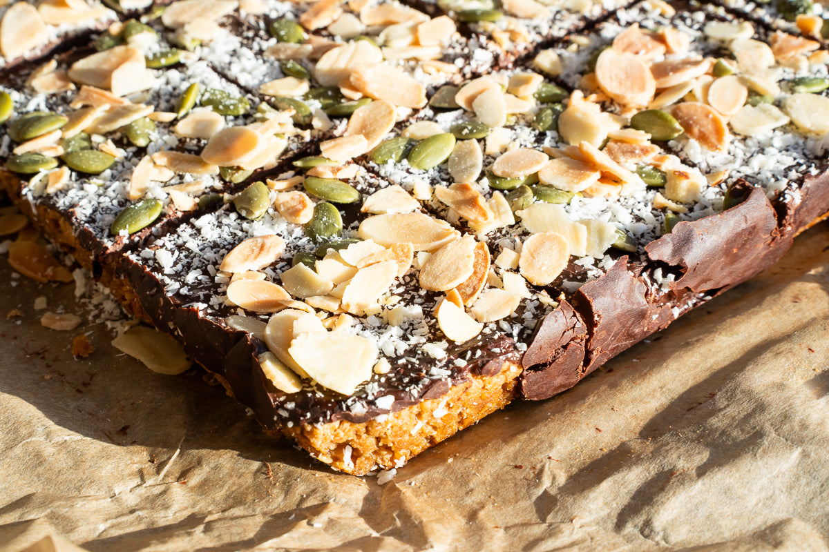 Chocolate Flapjack Close-Up - Vegan Gluten Free Oat Bar Topped with Almonds Pumpkin Seeds and Coconut | A Taste of Dreams Wholesale UK